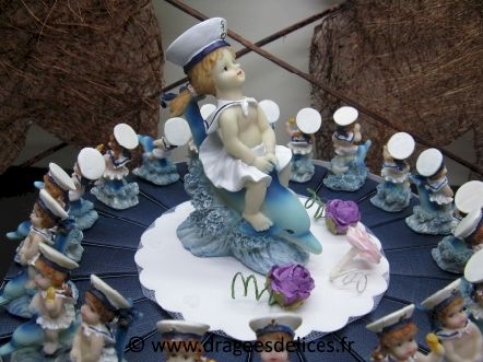 Gâteau à garnir de dragées pour un baptême fille sur dauphin : Sujet au centre du gâteau avec ses fleurs pour un baptême fille